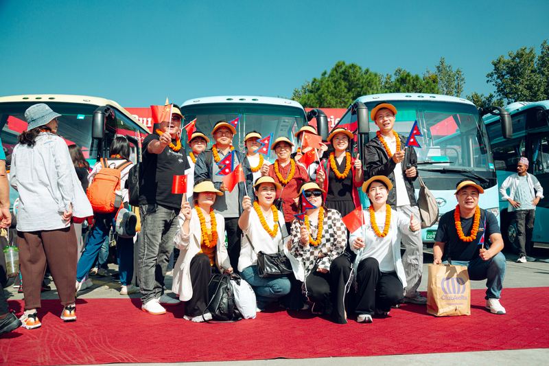 A group photograph with marigold garlands and both nations' flags